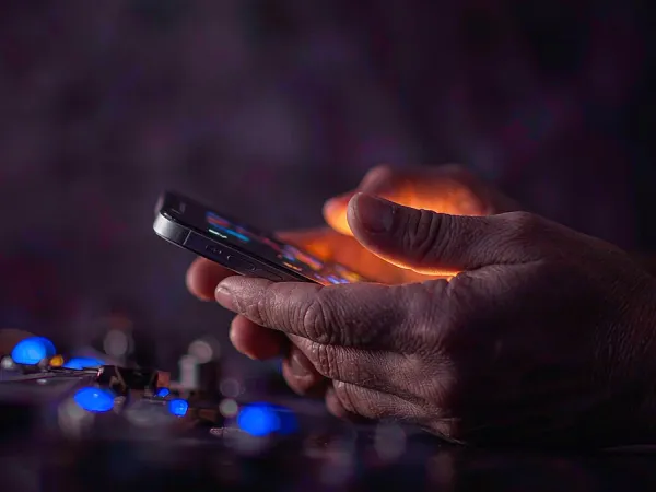 playrupees Hands holding a smartphone in warm light