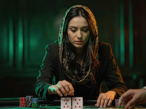playrupees Woman concentrating on two cards at a green felt blackjack table