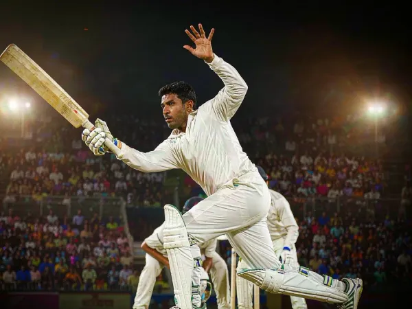 playrupees Cricketer in white playing a shot under lights in a packed stadium