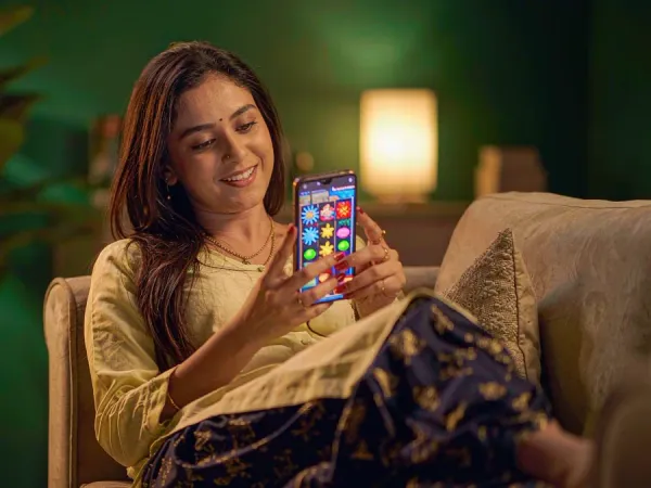 playrupees Woman smiling at a smartphone showing a colourful slot game