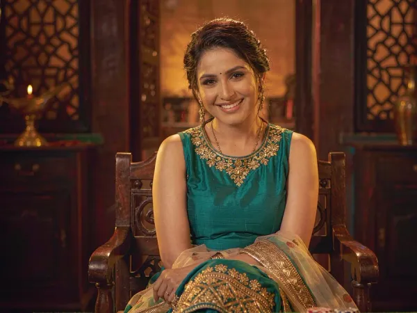 playrupees Woman in teal and gold smiling beside three face-up cards on green felt