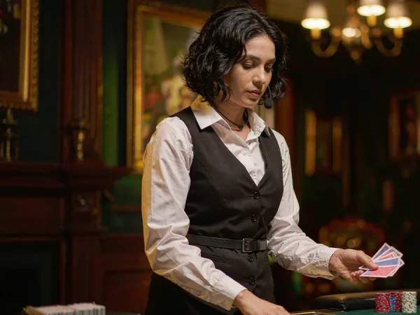 playrupees Dealer dealing cards onto a green baize table with chip stacks