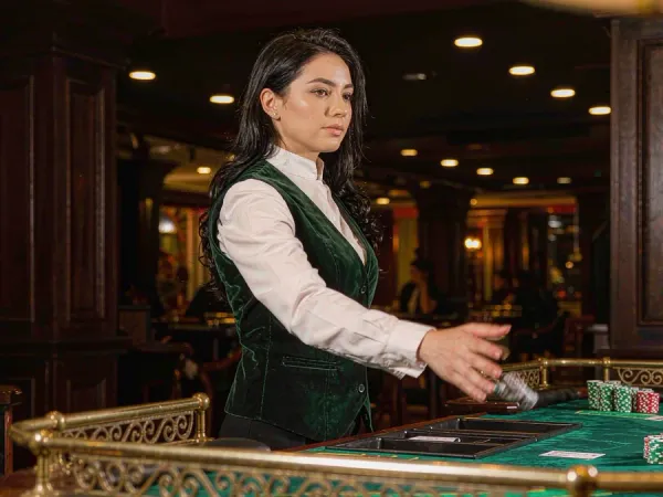playrupees Dealer revealing cards at a baccarat table with neat chip stacks